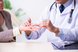 A doctor examines a patient's right hand with nerve damage
