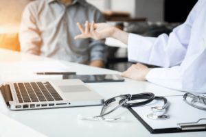 A doctor at a desk talking to a patient about cancer misdiagnosis. 