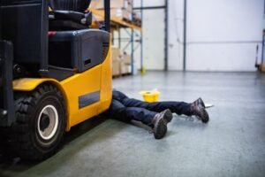 A man lying next to a fork lift truck after being injured in a forklift accident