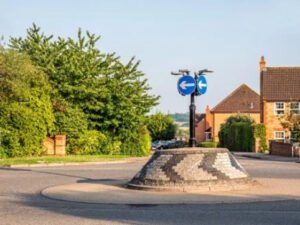 An empty roundabout with road markings and signs. 