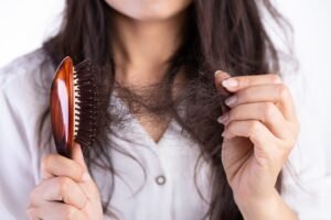 Woman brushing brittle hair with a brown brush. 