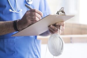 A doctor writes down notes on a clipboard