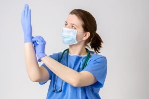 A doctor wearing a surgical mask ensures her gloves are properly fitted