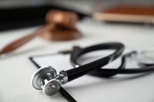 A stethoscope lies in front of a blurred gavel