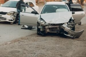 The front bumper of a silver car is smashed. 