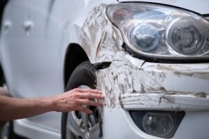 A man checking the front of his car that is damaged after a car accident.