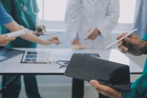 A group of professionals standing around a table and discussing medical care.