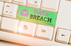 A close up of a white keyboard. On the shift key below the enter bar, there are the words 'data breach' written with a green background and a purple envelope symbol.