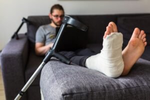A man sits on a sofa with a broken leg.