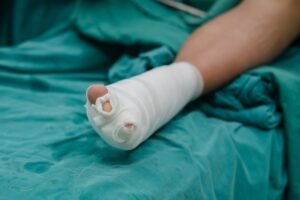 An injured foot in bandages on a bed with green sheets. 