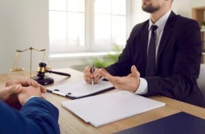 A solicitor works on a foot injury claim at a desk with a clipboard, scales and gavel. 