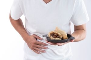 Someone holding a bowl of food and clutching their stomach because of food poisoning