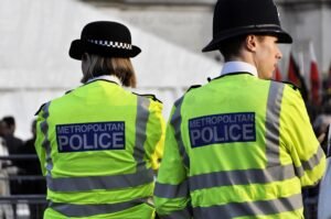 Two police officers patrol through a public space wearing high-visibility jackets.