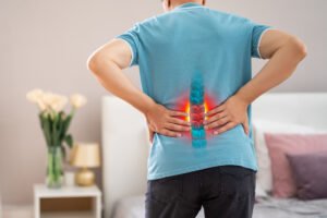 A graphic depicts a person holding their lower back, with their spinal pain highlighted in red