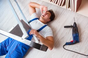 WORKER LAYING INJURED UNDER LADDER AFTER ACCIDENT AT WORK