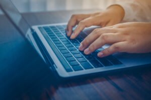 Closeup of a man's hands as he types on a laptop.