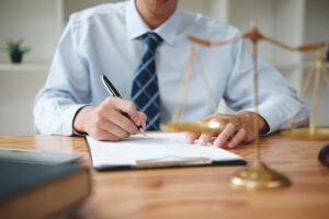 A solicitor takes notes behind a desk while discussing accident at work claims.