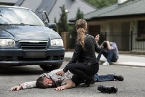A pedestrian lays in front of a car after being hit by it. 