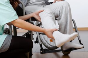 A nurse helps to move a patients leg.