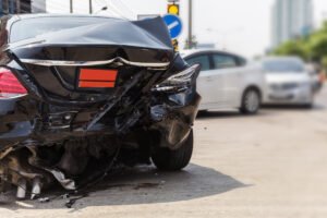 A black car shows visible damage to its rear after a road traffic accident.