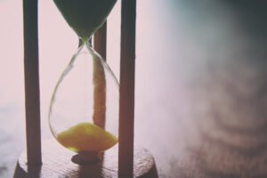 An hourglass with yellow sand on a brown background