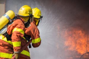 Two firefighters hosing a fire down.
