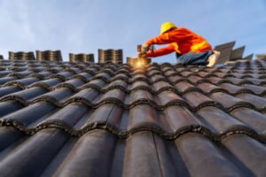 A worker in a hard hat fixes a roof.