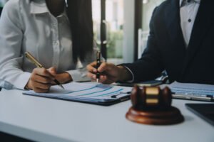 Two accident abroad claims solicitors sat on a desk with a gavel signing a document.