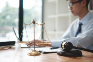 A pavement accident claims solicitor sat at his desk with a gavel and set of judgement scales.