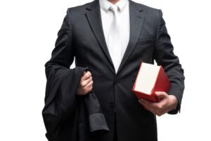 A prison injury claims solicitor in a suit carrying a jacket and red legal book.