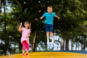 Kids on a school trip at an amusement park bouncing on a tramplene.