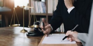 A fatal road traffic accident claim solicitor sat at a desk signing a document.