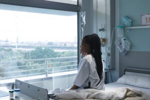 A female patient sits on a hospital bed.