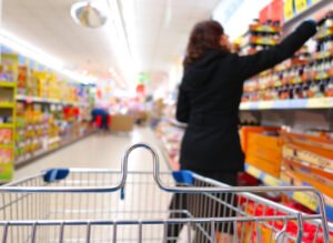 A woman reaching for something on the shelf in a supermarket.