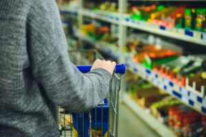 Someone pushing a trolley in a supermarket aisle. 