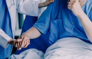 A healthcare professional comforting a patient who is sat up in a hospital bed after a missed diagnosis of lymphocytic leukaemia
