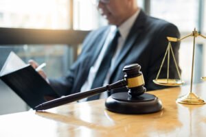 A solicitor at a table with a gavel and scales researching contraceptive negligence in a book. 