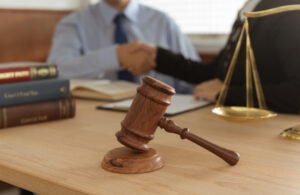 A solicitor and a client shaking hands in the background of a gavel on a desk after discussing surgical negligence claims.