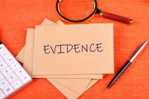'Evidence' written on a notecard with a magnifying glass and pen next to it