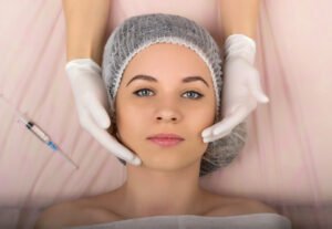A woman laying on a bed with a Botox needle and a beauty therapist