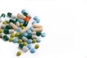A pile of tablets and capsules on a brilliant white background.