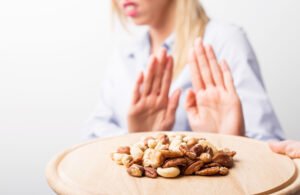 A woman with her hands out refusing a plate of nuts