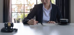 A solicitor sits at a desk taking notes for a passenger injury claim with a gavel beside her