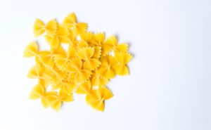 Uncooked bowtie pasta made with wheat flour on a white background 