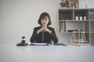 A solicitor sits at a desk working on gluten allergy claims with a gavel, scales of justice and pile of textbooks next to her