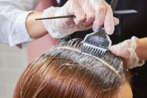 A woman receives hair dye treatment from a hairdresser.