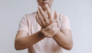 A person holds and massages their injured wrist, which is held up to the camera. 
