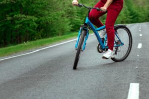 A man in a red tracksuit on a blue cycle on a road. 