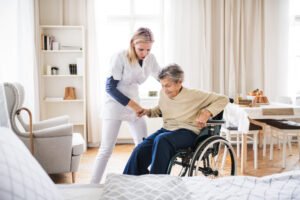 A care worker helping an elderly woman out of her wheelchair
