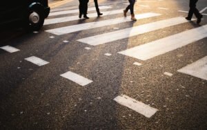 A taxi stopped at a zebra crossing as pedestrians use it. 